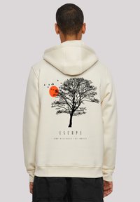 Cream-colored hoodie featuring a black tree silhouette, an orange sun, birds, and the text "ESCAPE AND DISCOVER THE WORLD" below.