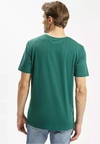 Zielona bawełniana koszulka z krótkim rękawem, okrągłym dekoltem i luźnym krojem. Widziana z tyłu prezentuje gładką teksturę i prosty design bez grafik.