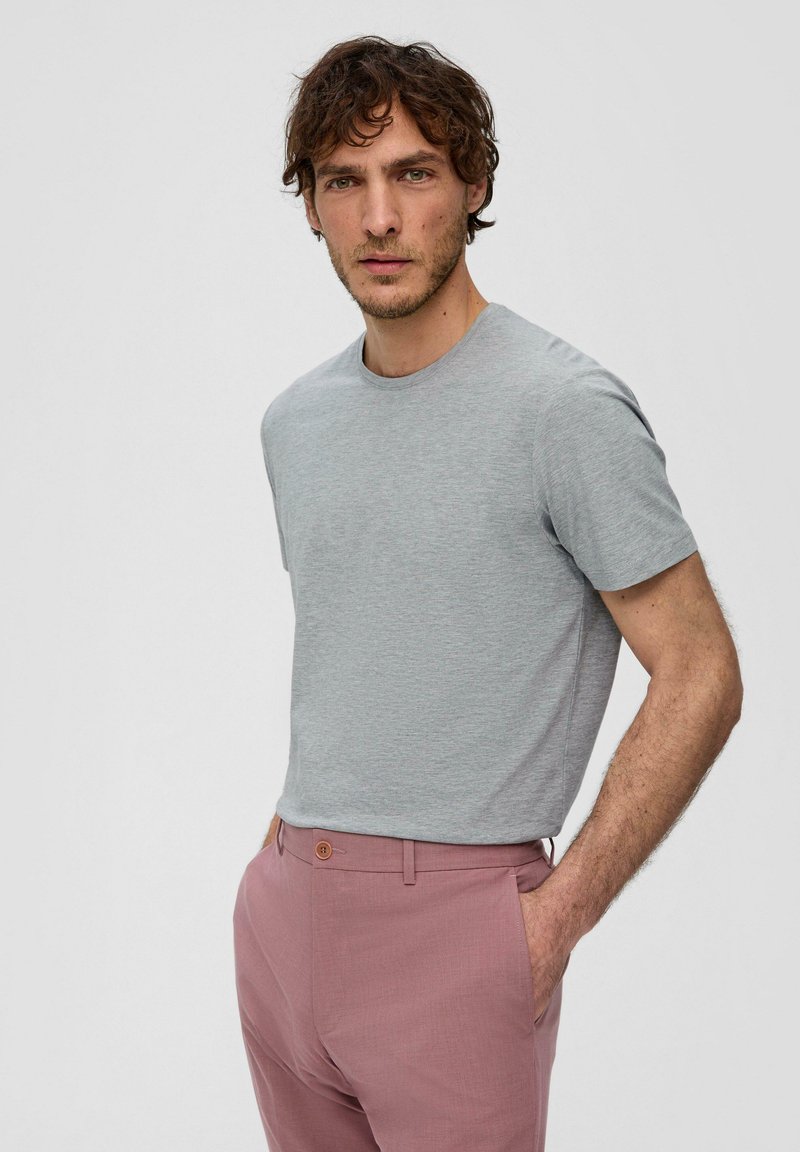 Grijze katoenen t-shirt met een ronde hals en korte mouwen, gecombineerd met op maat gemaakte roze broek met een knoop en zakken.
