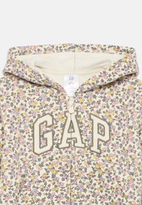 Felpa con zip floreale color crema, con fiori rosa, viola e gialli. Grande logo "GAP" in beige, materiale morbido e cappuccio.