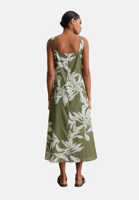 Grünes Leinenkleid mit floralem weißen Muster, breiten Trägern, einem quadratischen Rückenausschnitt und einer langen, fließenden Silhouette, mit einer subtilen Textur.