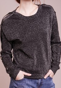 Maglione nero lavorato a maglia con brillantezza metallica, scollatura tonda, maniche lunghe e dettagli con bottoni su spalle. Tessuto morbido e vestibilità rilassata.