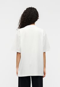 Λευκό t-shirt με κοντά μανίκια και άνετη εφαρμογή, κατασκευασμένο από μαλακό βαμβάκι. Διαθέτει διακριτικό λογότυπο στο λαιμό και λεία υφή.