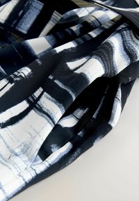 Čierna tkanina s bielymi a šedými abstraktnými ťahmi štetca, s hladkou textúrou a splývavým dizajnom. Mäkko a ľahký materiál.