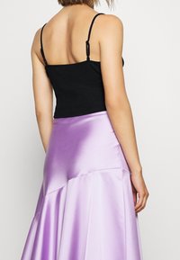 Czarny krótki top na ramiączkach w połączeniu z lawendową satynową spódnicą maxi, z szerokim krojem i gładką fakturą, z regulowanymi ramiączkami.