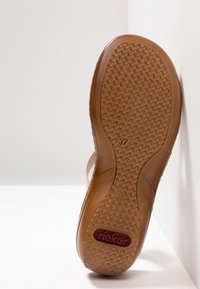 Semelle d'une sandale marron avec motif zigzag texturé, taille 37 indiquée, et logo rouge "rieker" près du talon sur fond blanc.