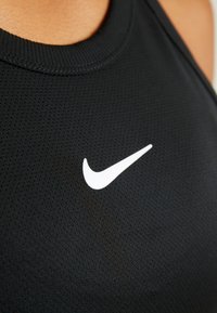 Top sportivo nero senza maniche con tessuto a rete testurizzato. Presenta un prominente logo Nike bianco sul davanti. Collo rotondo.
