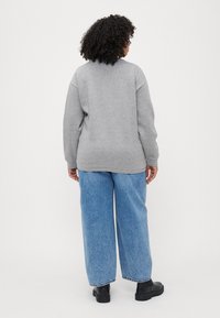 Gray sweatshirt with a relaxed fit and ribbed cuffs, paired with light blue wide-leg jeans and black ankle boots.