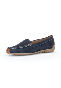 Mocassin en daim bleu marine avec un accent en cuir marron, des coutures blanches, un profil bas et une semelle en caoutchouc souple beige.