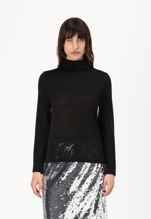 Black turtleneck top in a lightweight, slightly sheer fabric, paired with a sequined skirt featuring a silver and white pattern.