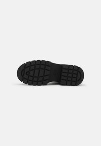 Black rubber shoe sole with deep tread pattern, size 37, shown from the bottom on a white background.