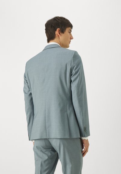 Costum bleu deschis, cu un design adaptat, având umeri structurați. Textură netedă și tipar subtil, dotat cu o deschidere unică la spate și pantaloni asortați.