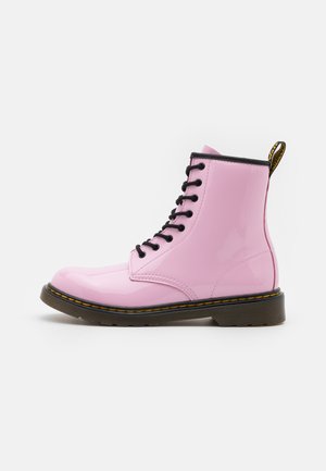 Stivale alla caviglia in pelle sintetica rosa con punta arrotondata, lacci neri, cuciture gialle e un pull tab con logo sul retro. Suola in gomma.