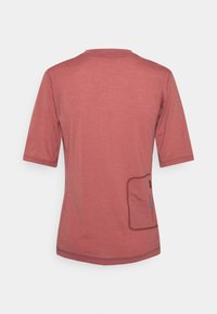 Camiseta de manga corta en color óxido con un escote redondeado y un detalle de bolsillo cosido en el lado izquierdo. Textura suave.