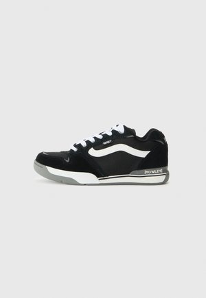 Black skate shoes with white accents, featuring a mix of suede and canvas materials, rounded toe, and rubber sole. Notable brand logo visible.
