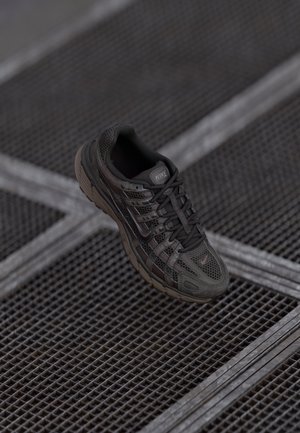 Buty do biegania Nike w czarnej siateczce z szarymi akcentami, z grubą podeszwą, zapięciem na sznurowadła oraz detalem logo na języku i boku.