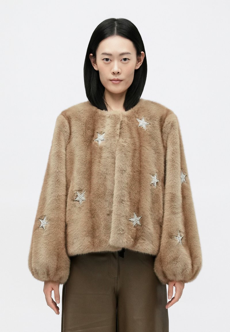 Pruun kunstnahast jakk kasti kujuga, kaunistatud hõbedaste tähemustritega ning volüümikate, kokku kogutud varrukatega. Sile tekstuur.