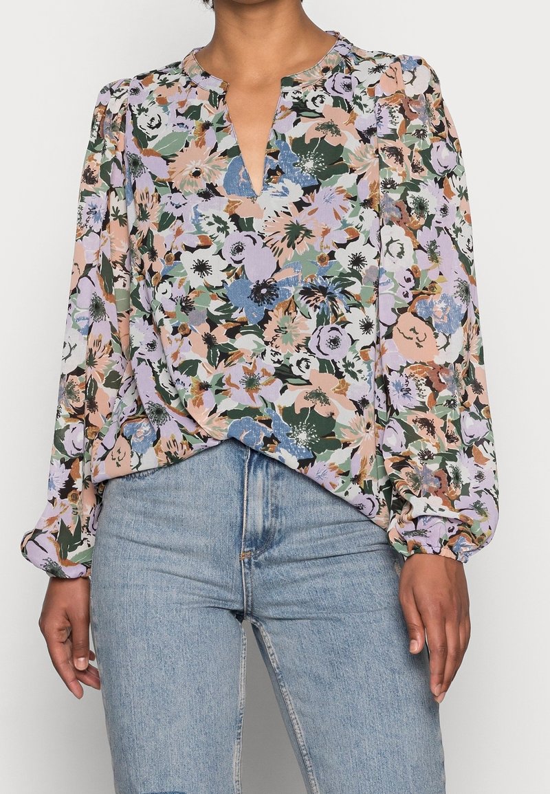 Blouse florale avec un col en V, des manches longues bouffantes et des épaules froncées. Présente un motif multicolore sur un fond clair.