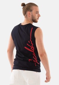 Schwarzes ärmelloses T-Shirt aus Baumwolle mit glatter Textur, das auf der Rückseite ein rotes handgeschriebenes Logo-Design aufweist.