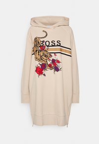 Sweat à capuche beige oversize avec un graphisme de tigre et des accents floraux, arborant le logo "BOSS", des rayures noires et dorées, ainsi que des ourlets latéraux zippés.