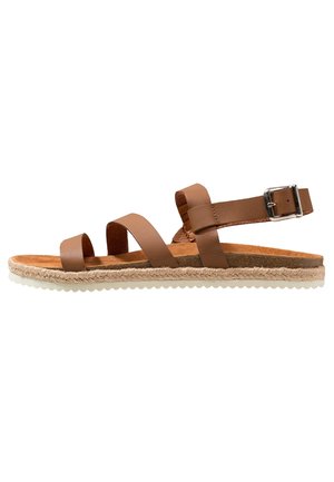 Sandale en cuir marron avec trois brides réglables, semelle en liège, détail en jute le long de la semelle et accent en boucle métallique.