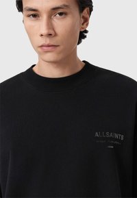 Μαύρο φούτερ με στρογγυλή λαιμόκοψη, κατασκευασμένο από απαλό ύφασμα. Διαθέτει μικρό ανάγλυφο λογότυπο "ALLSAINTS" στην αριστερή πλευρά του στήθους.