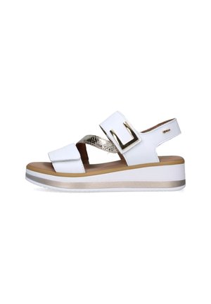 Sandali wedge bianchi con cinturini regolabili, caratterizzati da un accento dorato e dettagli metallici testurizzati. La suola è di colore marrone chiaro con una base bianca.