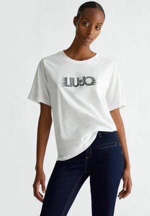 T-shirt bianca in cotone con maniche corte e scollatura rotonda, caratterizzata da una stampa grafica nera con la scritta "LIU•JO" in un carattere moderno.