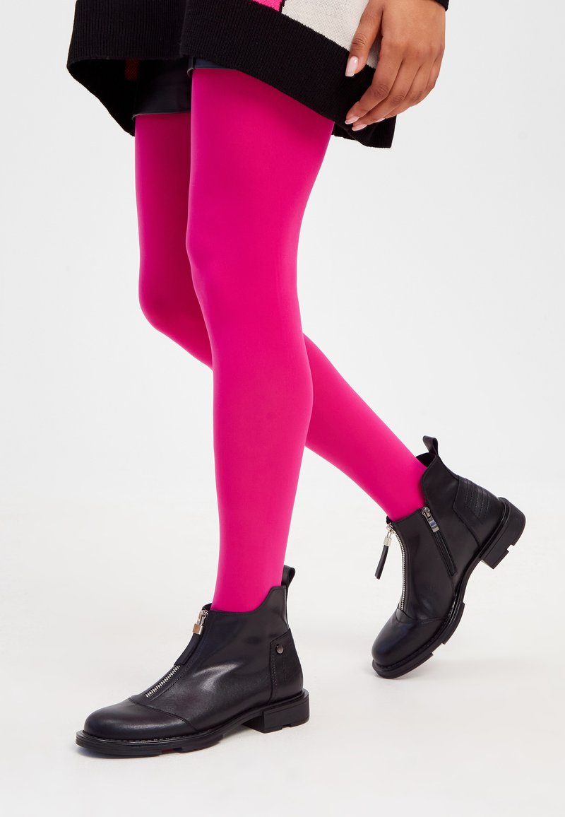 Stivali neri alla caviglia con zip laterale, abbinati a collant fucsia vivaci. Gli stivali presentano una texture liscia e dettagli sottili sul tallone.
