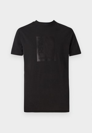 T-shirt nera in cotone con un logo rettangolare nero opaco sul davanti. Collo a giro con maniche corte e vestibilità regolare.