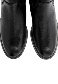 Bottes en cuir noir avec une finition texturée, bout arrondi et semelle plate. Présentent des coutures discrètes sans éléments métalliques visibles ni motifs.