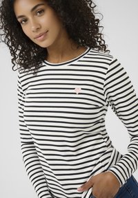 Zwart-wit gestreept shirt met lange mouwen, voorzien van een klein roze hartapplicatie op de linkerborst, met een ronde halslijn en een aansluitend model.