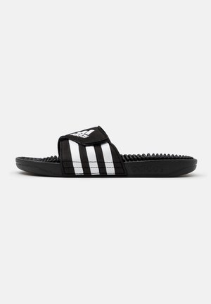 Schwarze Adidas Slide-Sandale mit verstellbarem Riemen, weiß gestreift in drei Streifen, und einer strukturierten Fußbett-Oberfläche für Massageeffekt.