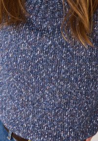 Un pull en tricot dans des tons de bleu et de violet, avec un col côtelé et un motif texturé et épais. Texture douce visible partout.