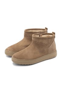 Ein Paar braune Wildleder-Stiefeletten mit beigen Gummisohlen und Fleece-Fütterung, die entlang der oberen Kante mit Zickzacknähten verziert sind.
