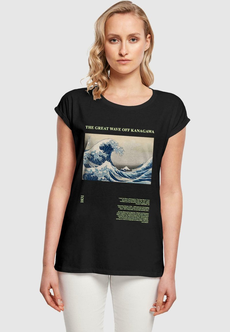 Camiseta negra de manga corta con una impresión de "La Gran Ola de Kanagawa" en azul y blanco, con texto verde detallado debajo de la obra.
