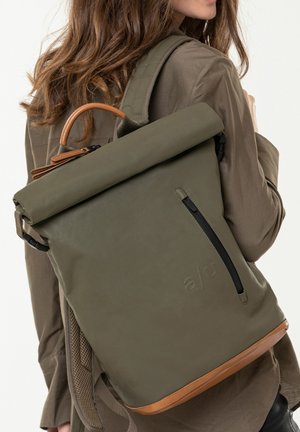Roll-top backpack in olive green material with a smooth texture, features a brown leather base and a side zipper pocket.
