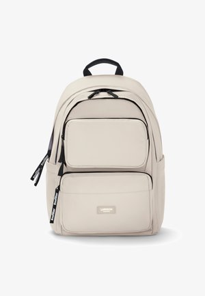 Lichtbeige rugzak met meerdere compartimenten, zwarte ritsen en banden. Voorzien van een gevoerde rug en een handvat aan de bovenkant om te dragen.