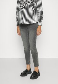 Bluză cu dungi alb-negru și talie legată, purtată cu blugi skinny gri și mocasini negri din patent cu accente cu tinte.