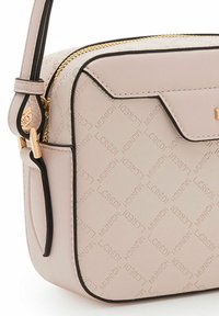 Bolso cruzado de color rosa claro, feito de material texturizado, con cremallera dorada, ribete negro y patrón de logo en relieve en la superficie.