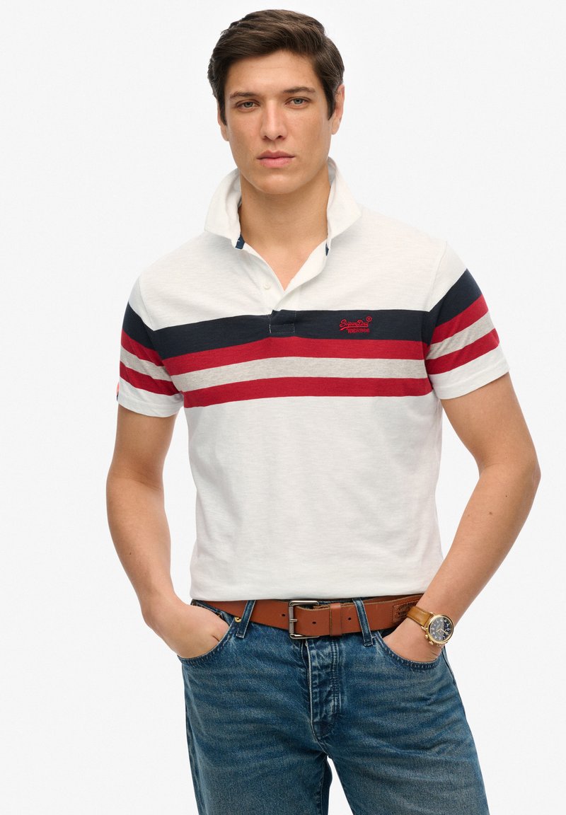 Hvid polo skjorte med navy og røde vandrette striber, korte ærmer og krave. Sammen med blå jeans og et brunt bælte.