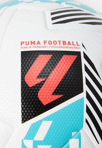 White soccer ball with textured surface, featuring red and black logo, blue accents, and geometric patterns, branded with "PUMA FOOTBALL."