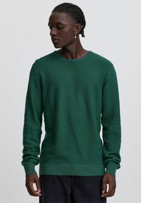 Grüner Strickpullover mit strukturiertem Muster, Rundhalsausschnitt und langen Ärmeln. Gerippte Bündchen und Saum verleihen dem Design Details.