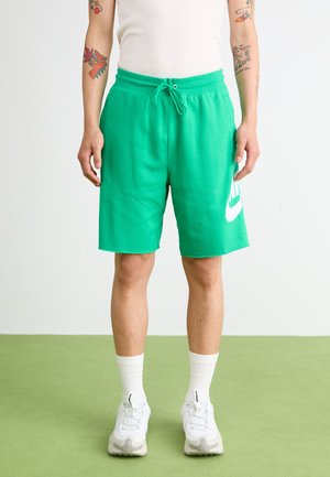 Zelene atletske šortse izrađene od mekanog materijala, s elastičnom tankom i bijelim Nike logom na lijevoj nozi. Nosene s bijelim tenisicama.