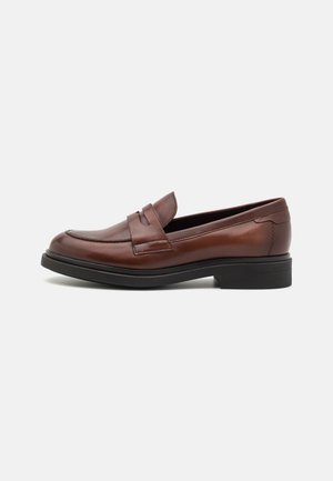Brązowe skórzane penny loafer z czarną podeszwą, zaokrąglonym noskiem, niskim piętą i paskiem na przodzie, pokazane z profilu.