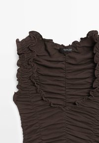 Hnědý top bez rukávů s nařaseným výstřihem a shromážděnou texturou, se štítkem značky, vyrobený z lehkého materiálu.