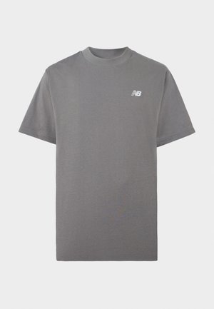 Siva majica s kratkimi rokavi in okroglim izrezom, z majhnim belim logotipom New Balance na levi strani prsnega koša, na enobarvni podlagi.