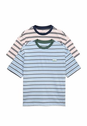 Due T-shirt a maniche corte a righe, una azzurro chiaro con colletto verde scuro e logo, l'altra panna con colletto blu navy, distese e sovrapposte.