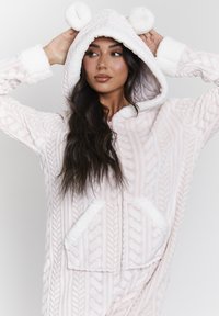 Fleecejumpsuit w jasnoróżowym kolorze z wzorem w warkocze, puchata kieszeń z pomponami, przednie kieszenie z puszystym wykończeniem oraz pełne zapięcie na zamek.