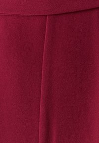 Burgundno teksturirano blago z gladko površino. Ponaša se z detajlom šiva za dodano dimenzijo. Primerno za krojene obleke.